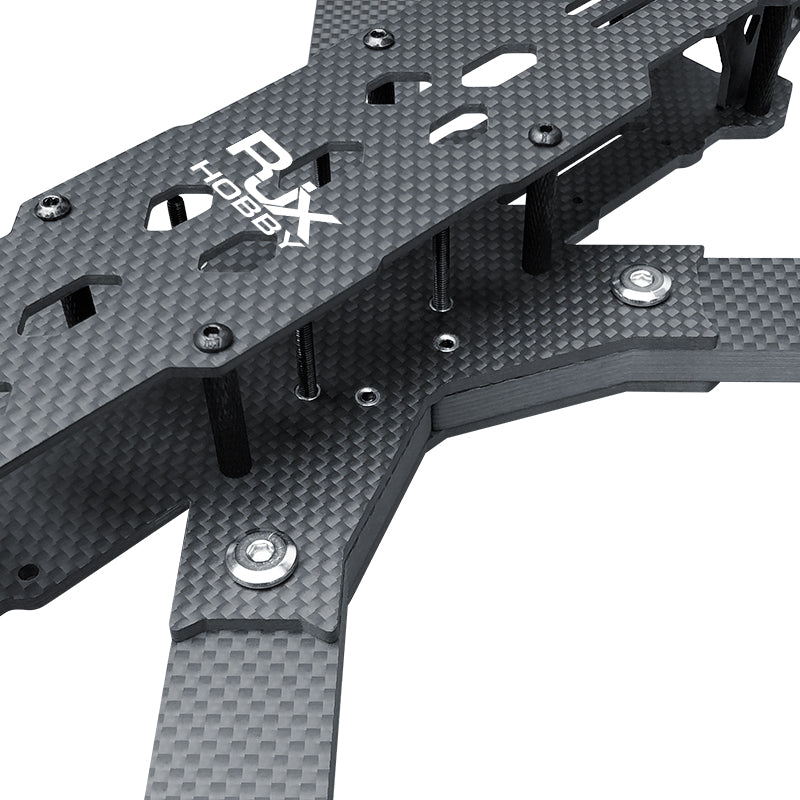 Close-up of RJX carbon fiber FPV drone frame top and arm plates with standoffs, screws, and mounting cutouts