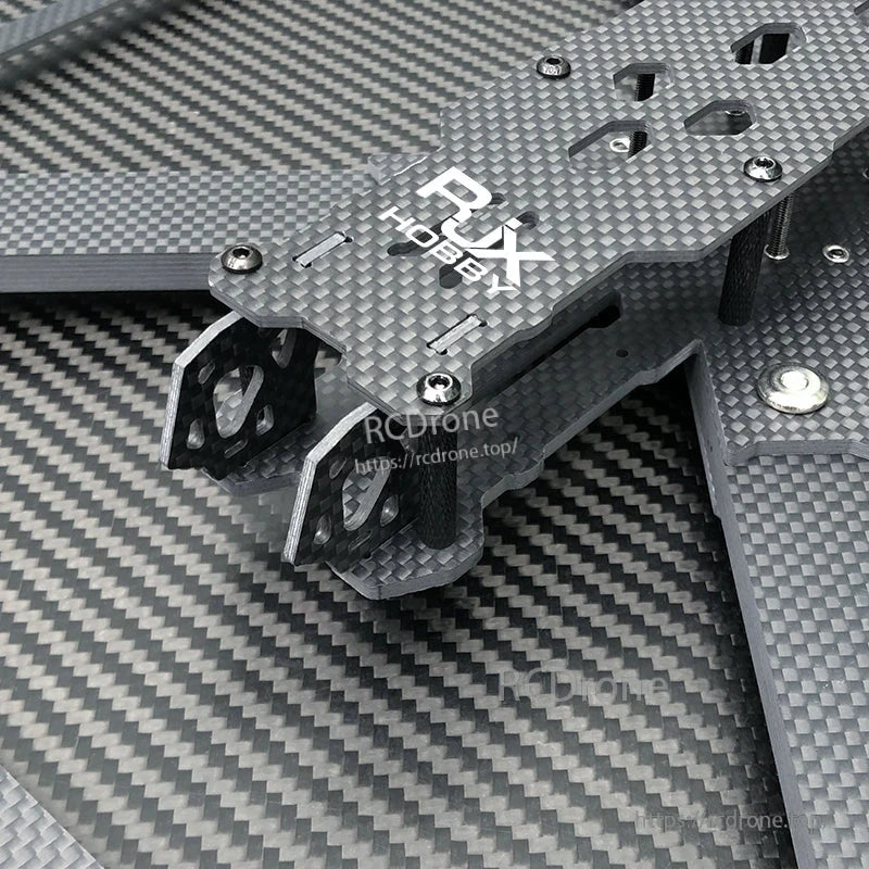 Close-up of RJX carbon fiber FPV drone frame top plate with standoffs, screws, and mounting holes