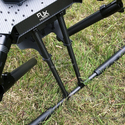 RJX1300C carbon fiber folding quadcopter frame landing gear with triple struts and tubular skids resting on grass