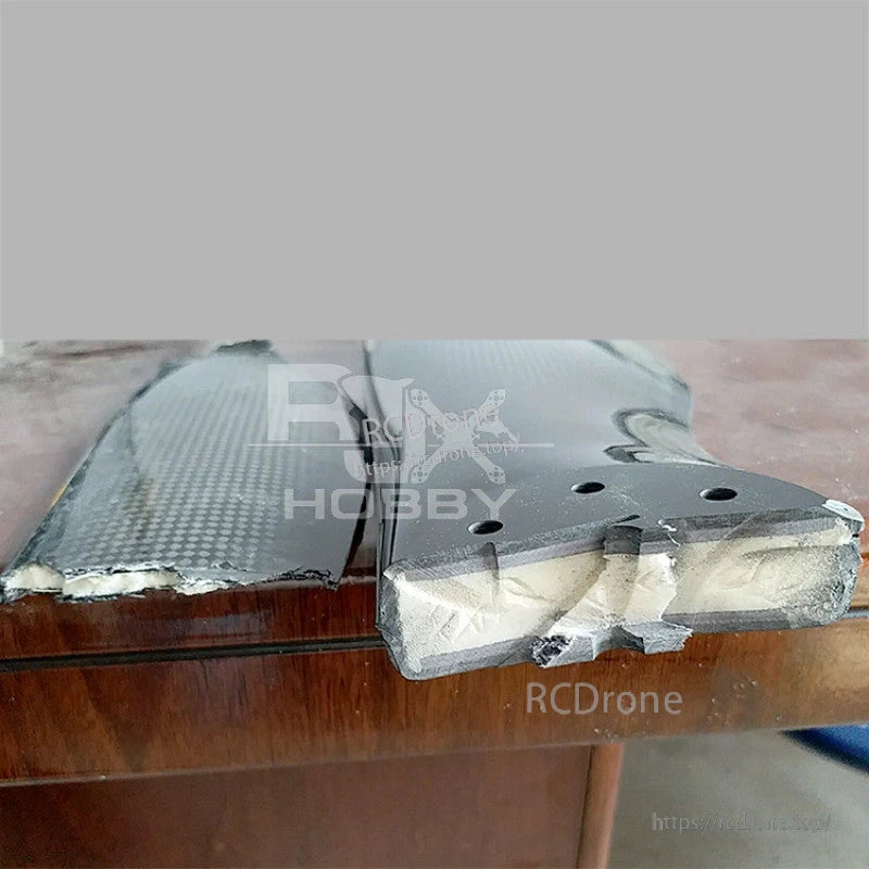 Close-up of RJXHOBBY carbon fiber drone propeller blades with pre-drilled mounting holes and protective wrap