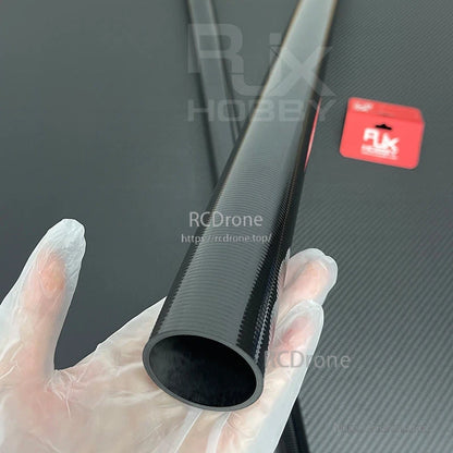 Carbon fiber tapered cone-shaped tube with hollow end and visible weave pattern, held in a gloved hand