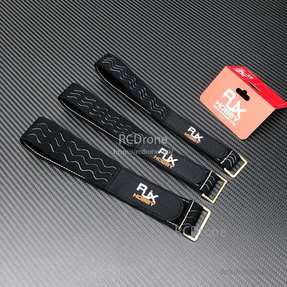 Black RJXHOBBY non-slip silicone battery straps with wavy grip pattern and metal buckles on a carbon-fiber surface