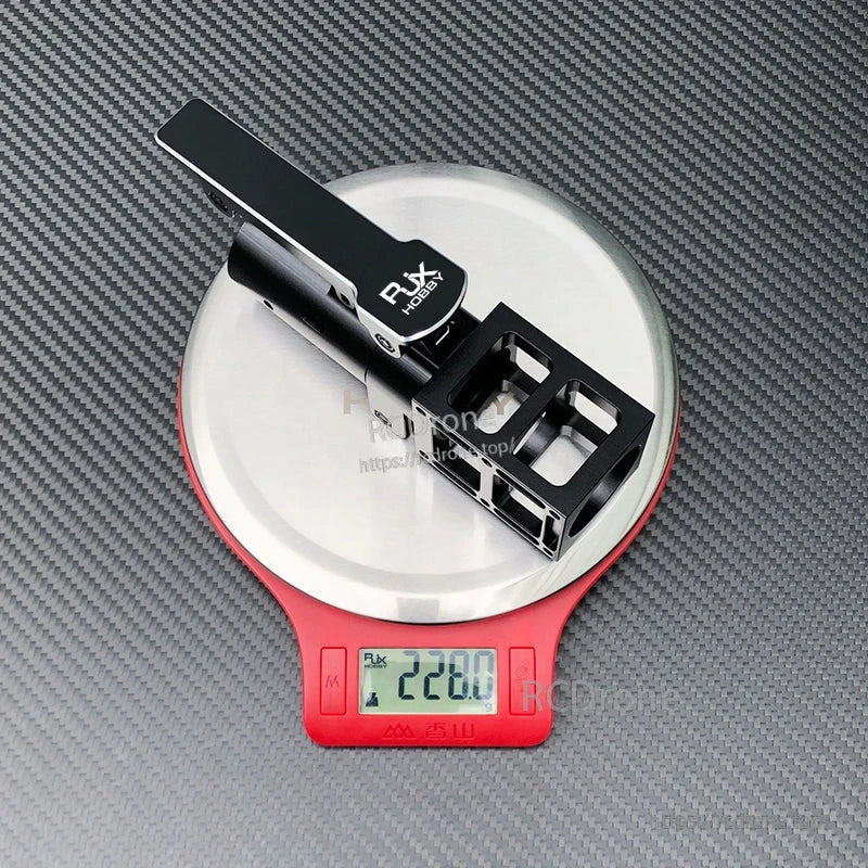 RJXHOBBY black aluminum folding side arm with hinge mount for UAV, resting on a scale reading 228g