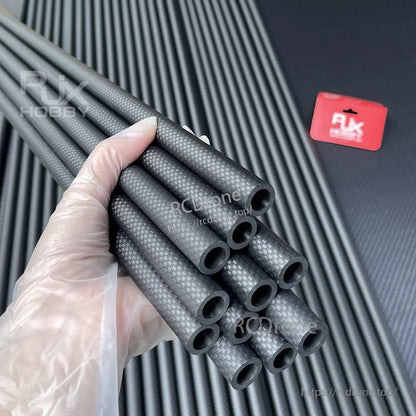 Hand holding RJXHOBBY 3K carbon fiber round tubes with twill weave finish and hollow ends