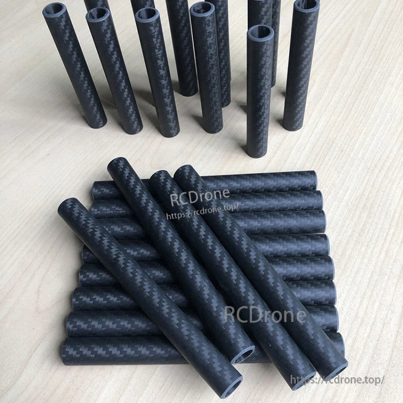 RJXHOBBY 3K Carbon Fiber Round Tube, Stack of round 3K carbon fiber tubes with matte woven finish, shown in multiple cut lengths on a tabletop