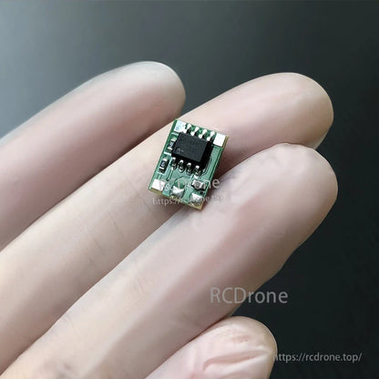 Micro brushed RC ESC module on a fingertip, small green PCB with IC chip and solder pad connections
