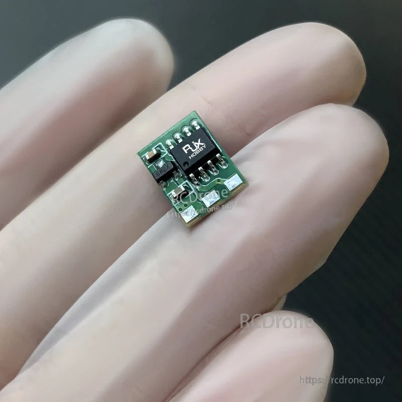Tiny RJXHOBBY brushed RC ESC module on fingertip, micro green PCB with solder pads and 8-pin chip