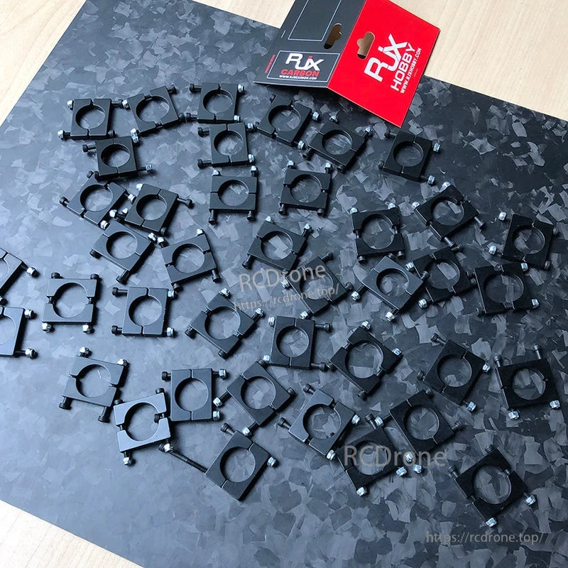 Collection of RJXHOBBY black anodized aluminum pipe clamps with mounting screws on a patterned surface