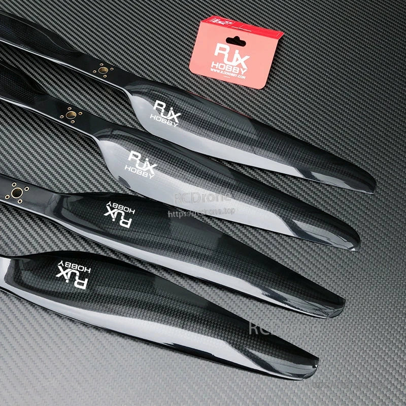 RJXHOBBY carbon fiber propeller blades with glossy black finish laid out on a textured carbon surface
