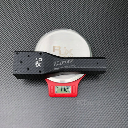 RJXHOBBY carbon fiber UAV arm on digital scale reading 142.5 g, with multiple mounting holes and matte carbon texture.