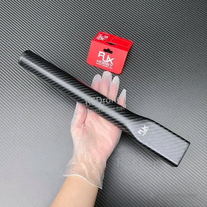 RJXHOBBY carbon fiber UAV arm tube with flattened mounting end, held in hand beside red RJX packaging