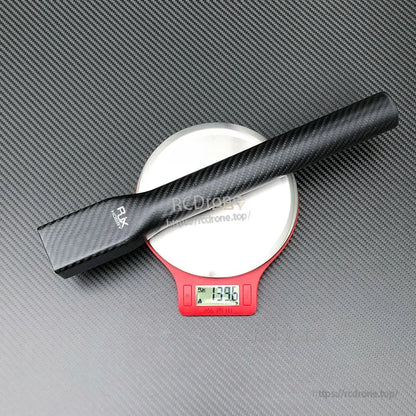 Carbon fiber UAV multicopter arm tube on a digital scale, showing an approximate weight of 129 g