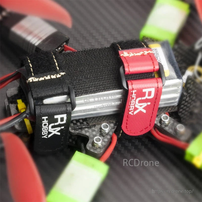 RJXHOBBY Non-Slip Silicone Battery Strap, RJXHOBBY hook-and-loop battery strap with metal buckle securing a LiPo pack on an FPV drone frame