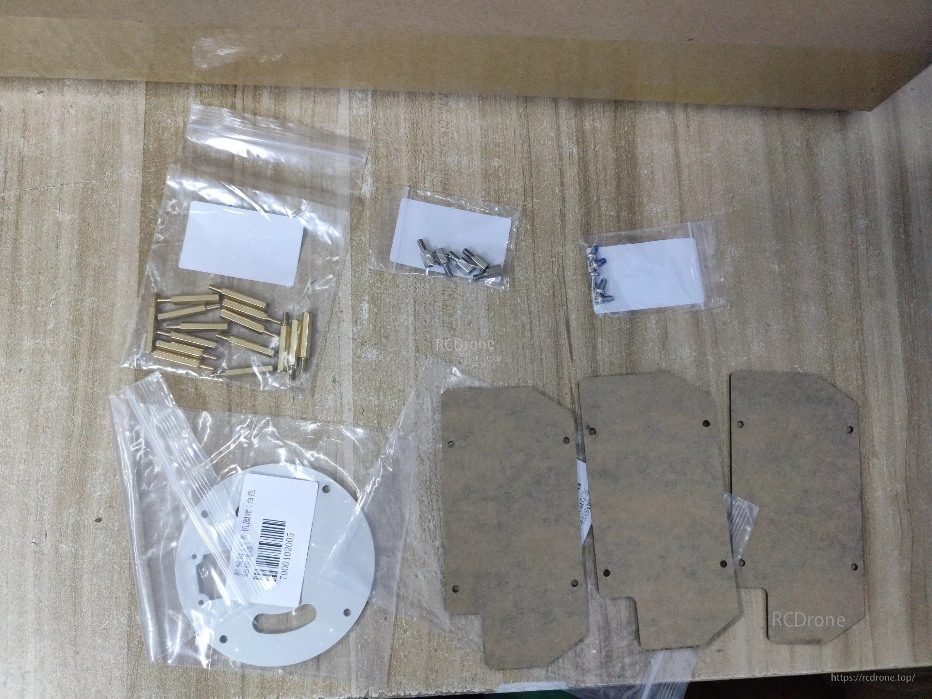 Close-up of included hardware set: brass standoffs, assorted screws, white circular plate and three mounting panels