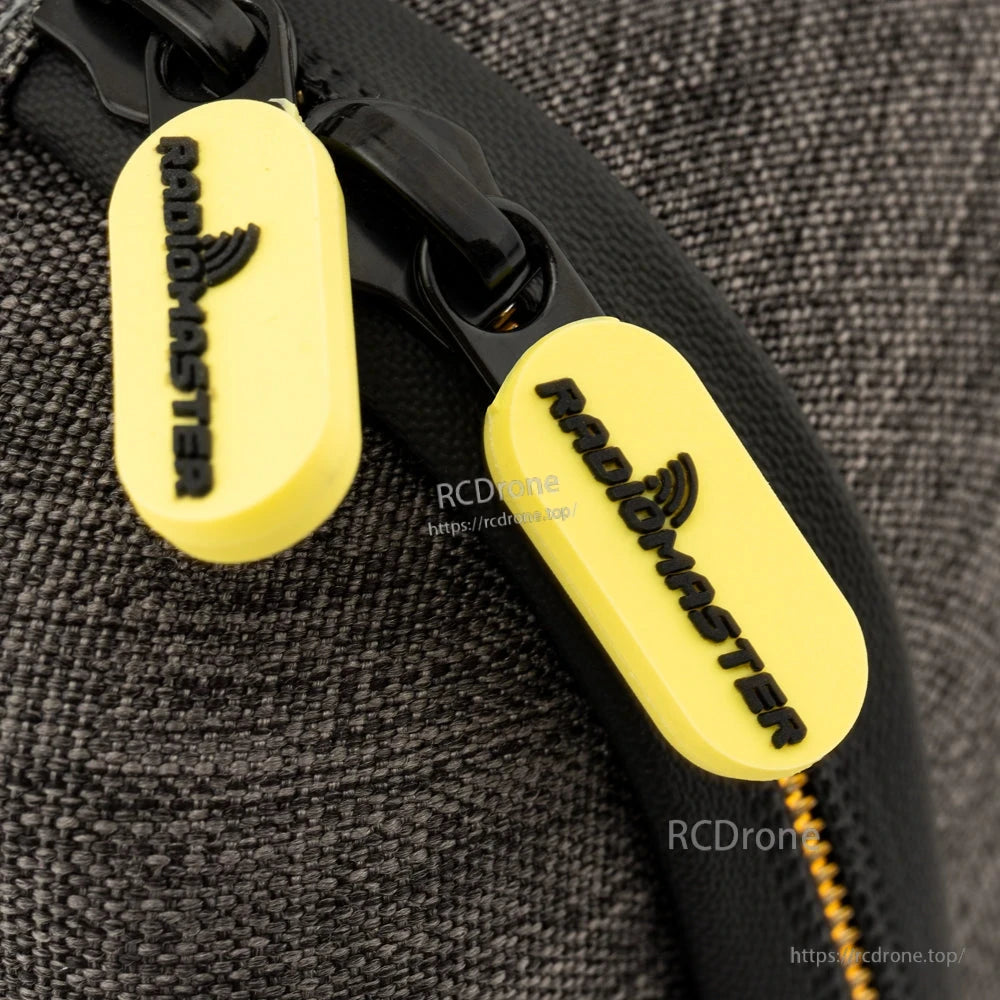 Close-up of yellow RadioMaster zipper pulls on black zipper track and grey fabric shell