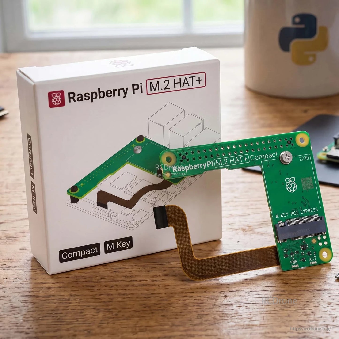 Retail box and Raspberry Pi M.2 HAT+ Compact board with attached ribbon cable on tabletop