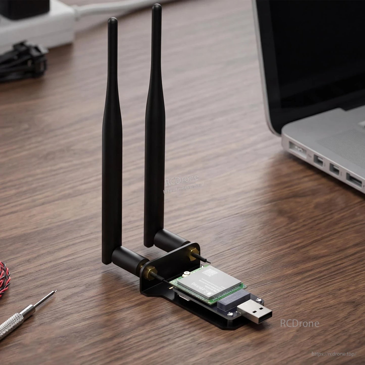 Desktop setup with SIM7600 module on USB adapter and two antennas beside a laptop