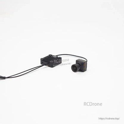 FPV camera and SKYZONE air unit linked by cable, camera front lens view with transmitter in background