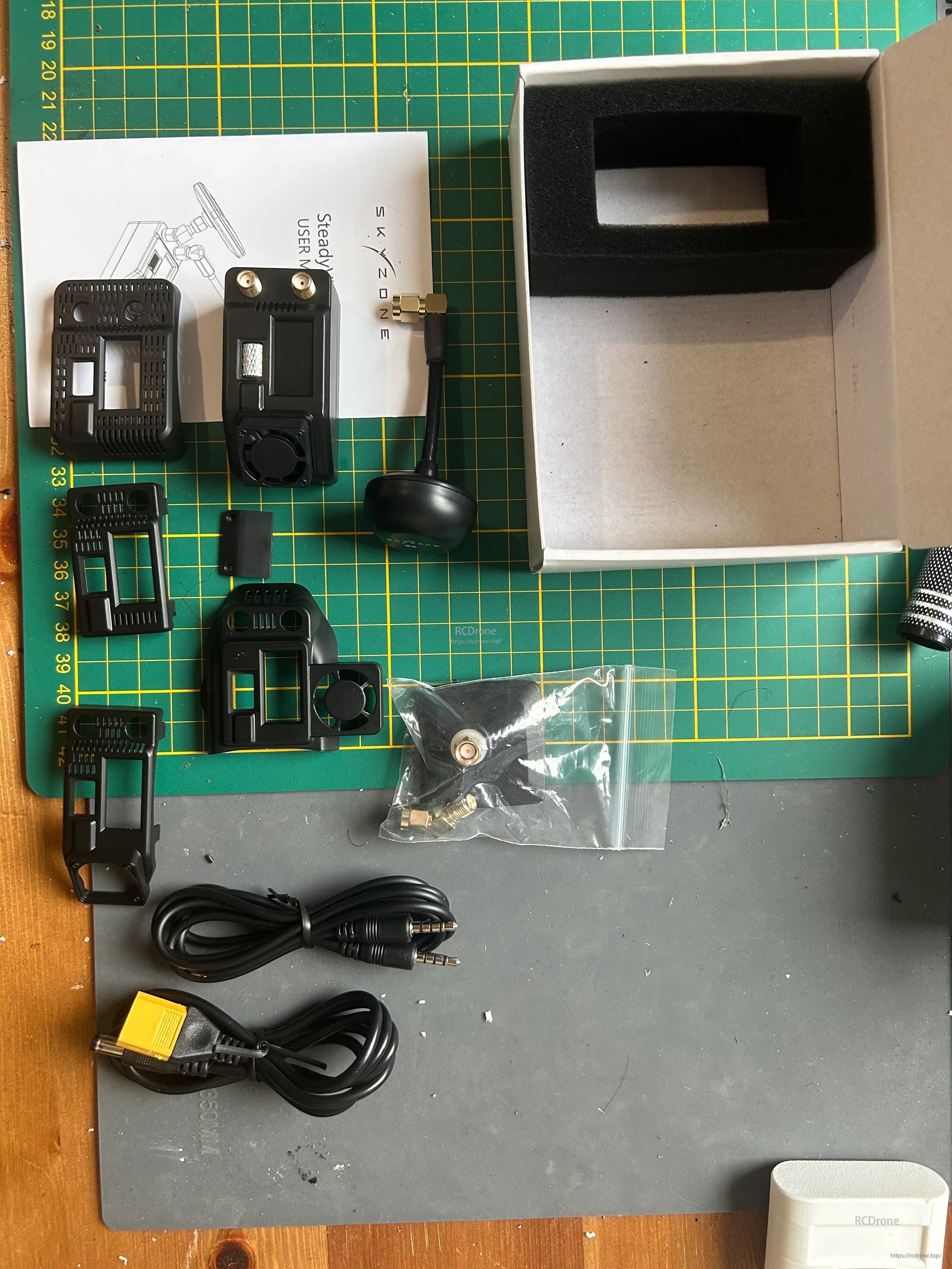SKYZONE STVX Steadyview X parts and accessories laid out with manual, antenna lead, and bay cover pieces