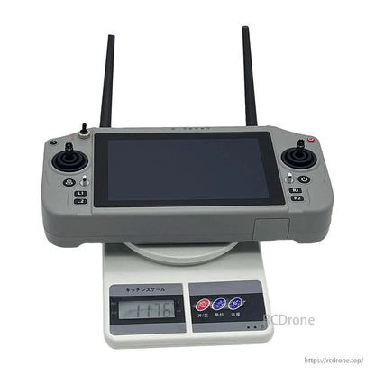 Skydroid G20, A remote control, featuring two antennas and a screen, weighs 117.6 grams as shown on a digital kitchen scale.