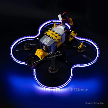 Cinewhoop-style FPV drone with blue-purple LED strip lighting wrapped around the prop guards