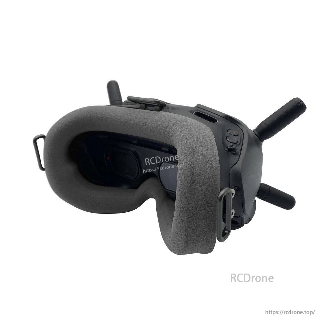 Three-quarter view of DJI FPV goggles wearing gray foam face pad, showing side buttons and antennas