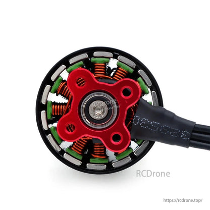 Underside view of FPV brushless motor showing red mounting base, bearing, stator, and wire lead