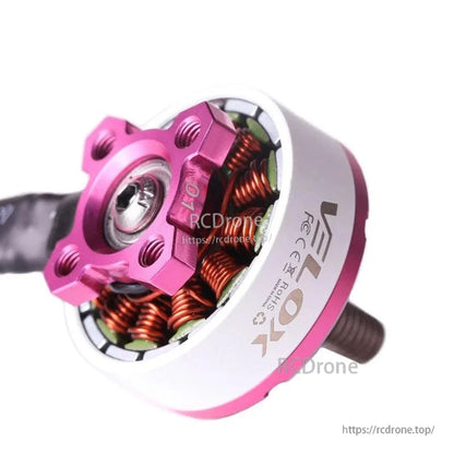 Close-up of a T-Motor brushless drone motor with pink top mount, white housing, and exposed copper windings