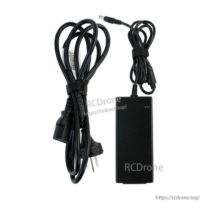 AC adapter power supply with US 2‑prong power cable and attached DC barrel connector lead, flat lay