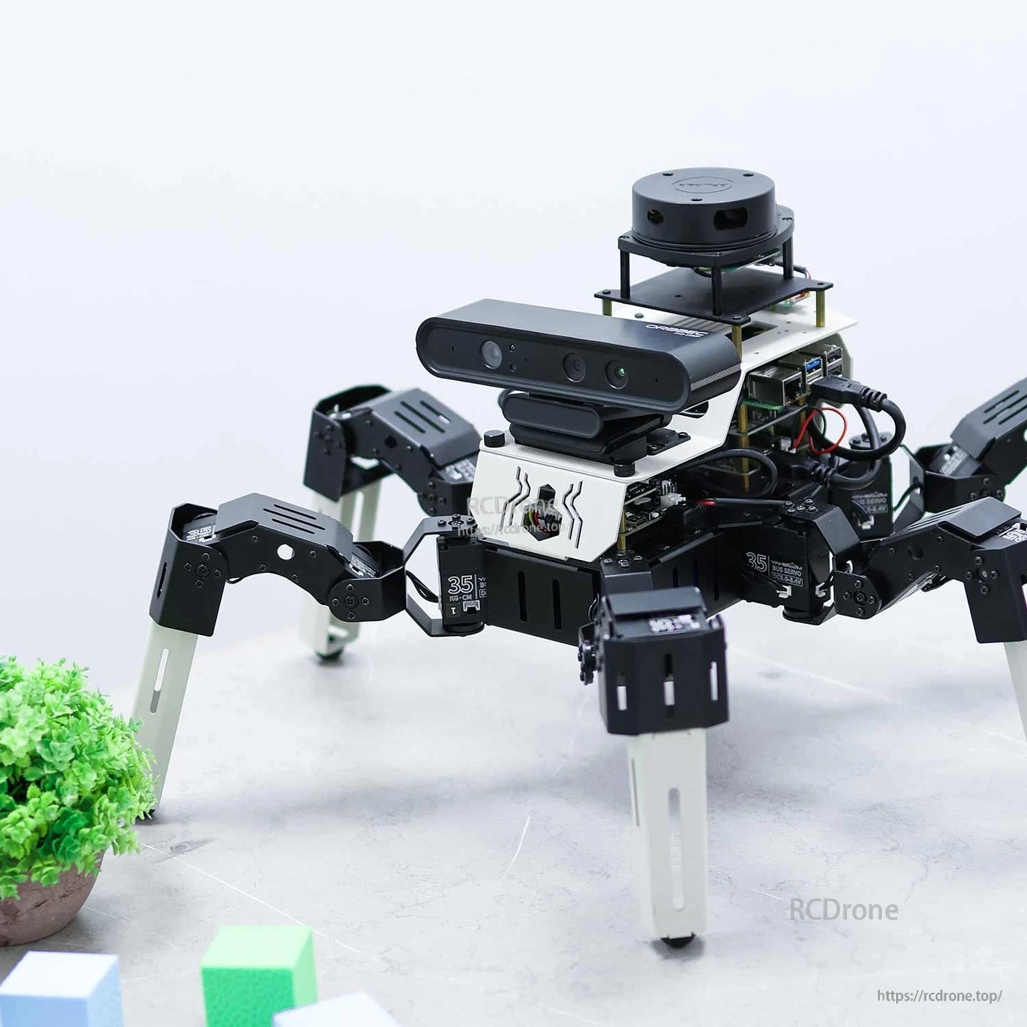 Three-quarter view of hexapod robot on tabletop with depth camera bar and stacked top sensor module