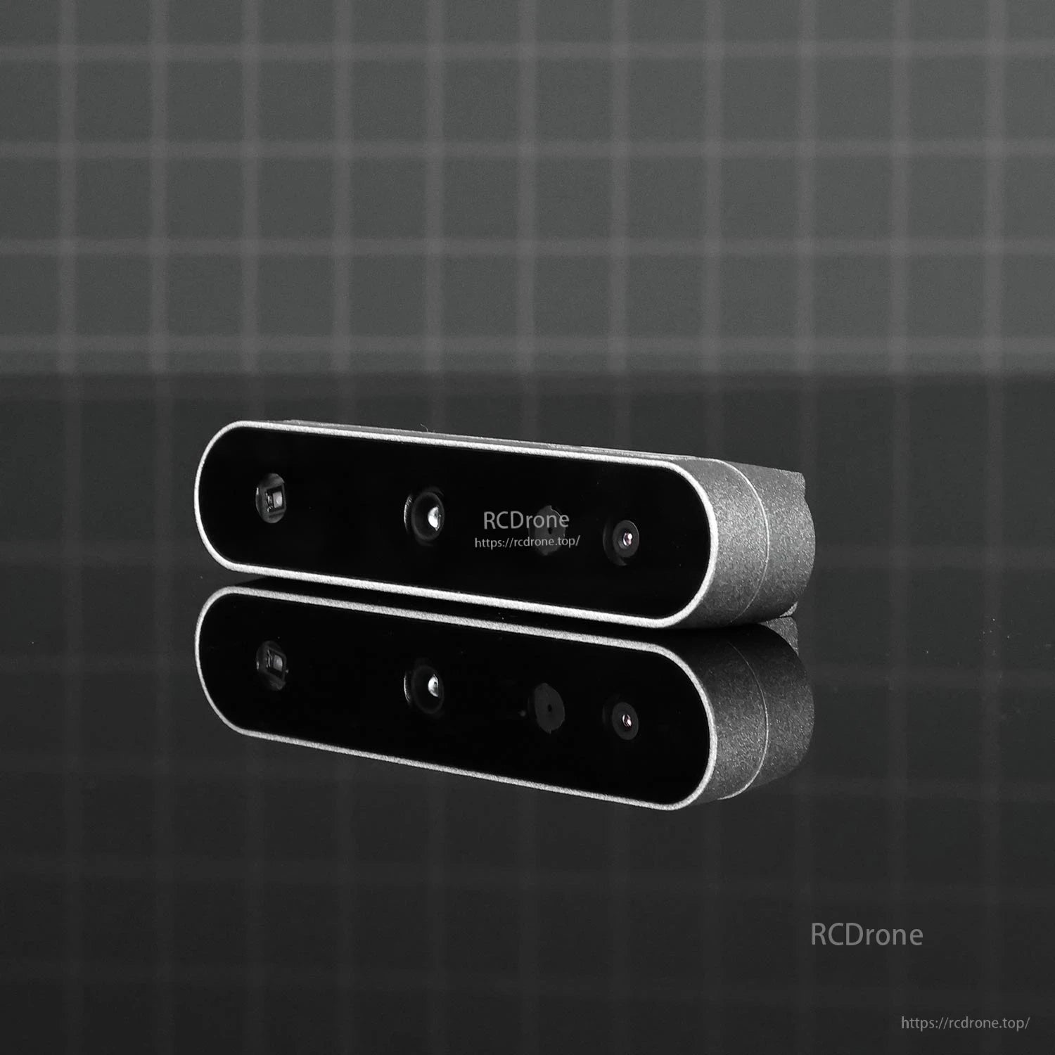 Low-light product photo on dark grid background showing front face and lens layout