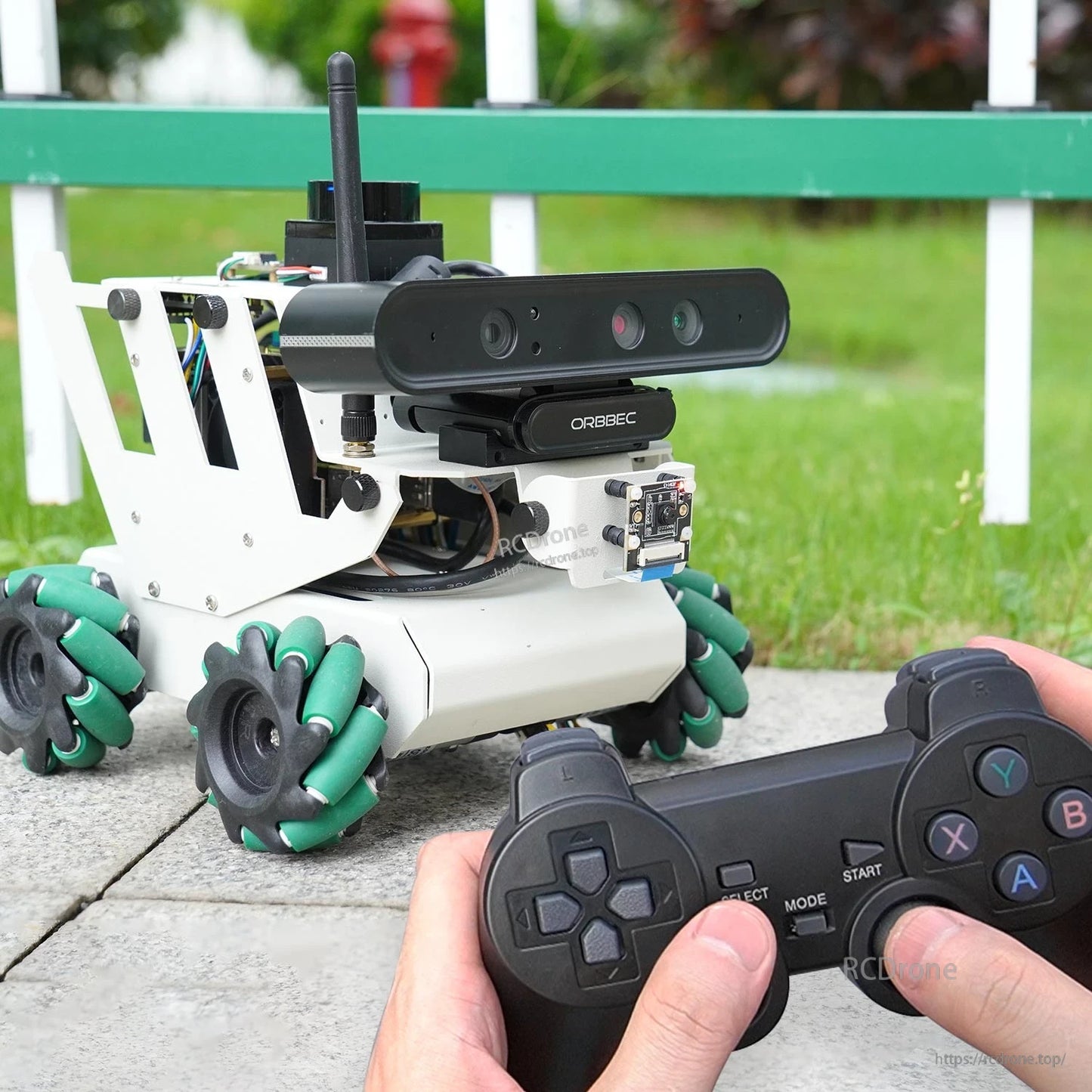 Robot car being operated with handheld game controller outdoors, front view with depth camera visible