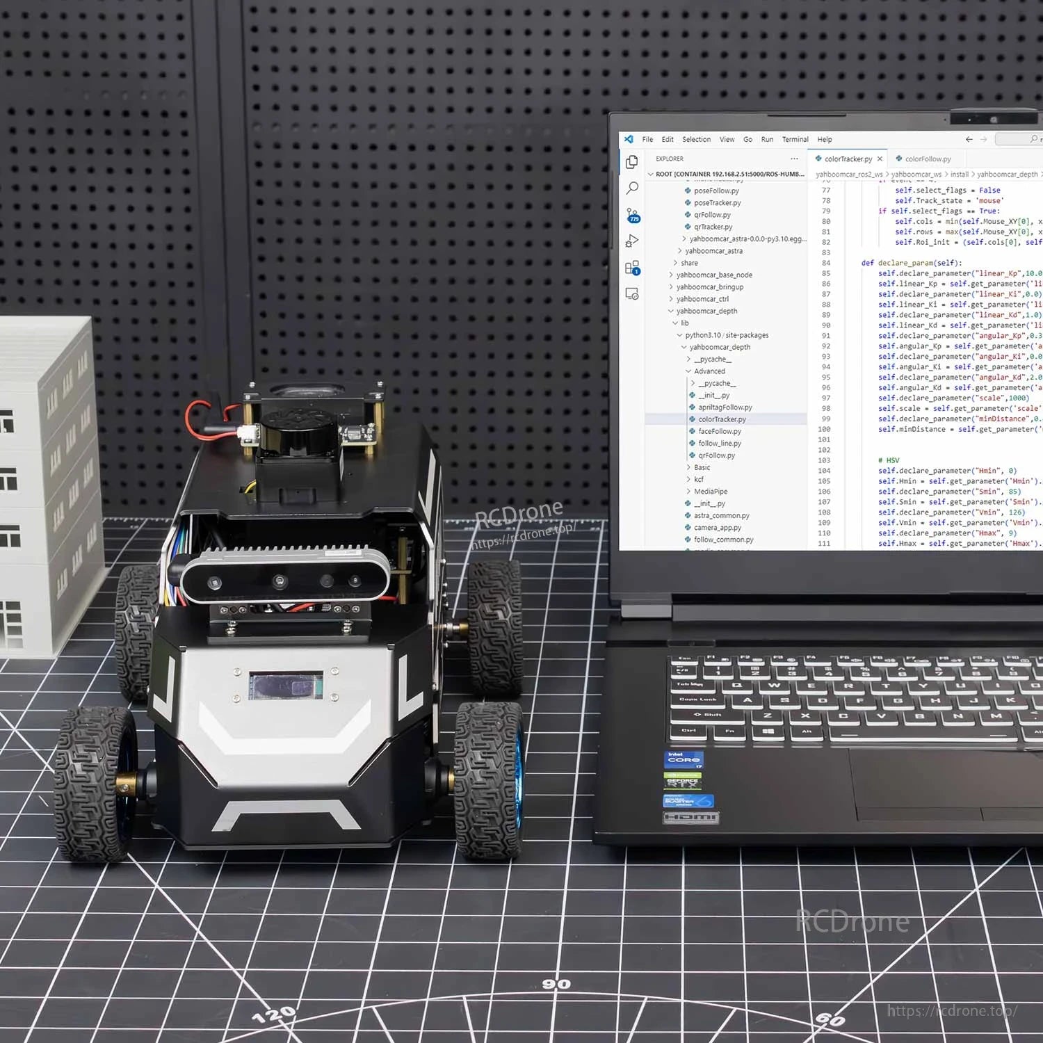 Front view of robot car next to laptop running code, indoor desktop test setup