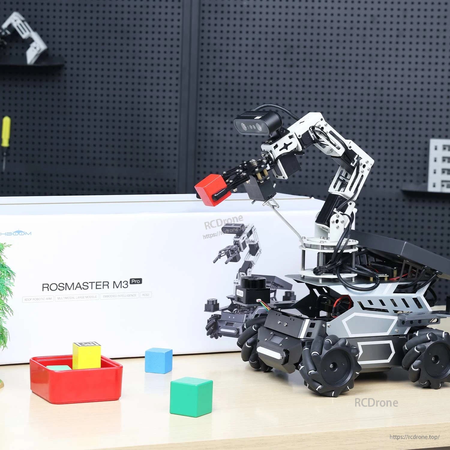 Yahboom ROSMASTER M3 Pro ROS2 Robot with 6DOF arm picking up a cube, box packaging in background