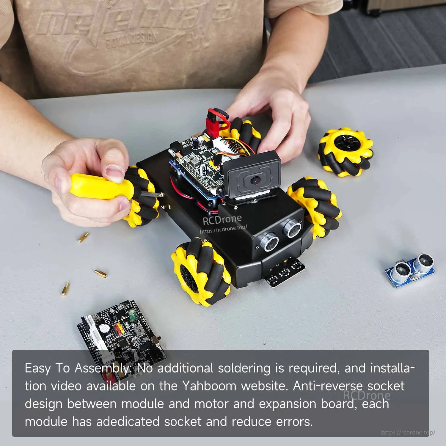 Hands assembling the robot car chassis with screwdriver, showing plug-in modules and wheels
