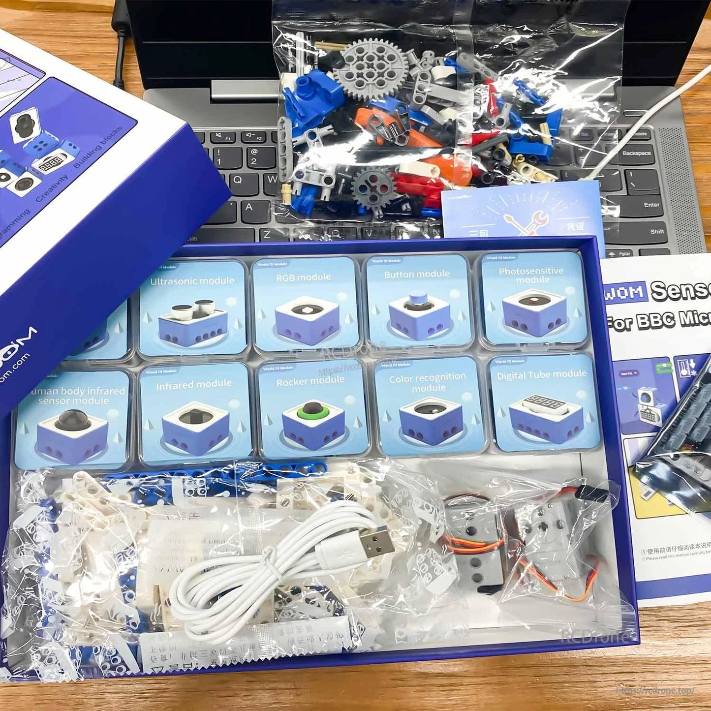 Unboxed Yahboom micro:bit sensor kit in tray with labeled modules, building pieces, cables and instruction booklet
