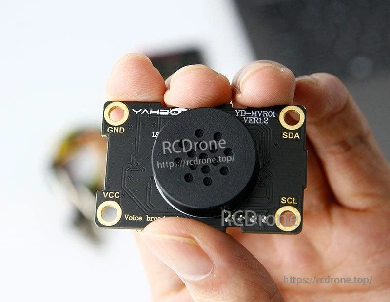 Handheld size reference of Yahboom voice broadcast board with speaker and labeled GND/VCC/SDA/SCL pads