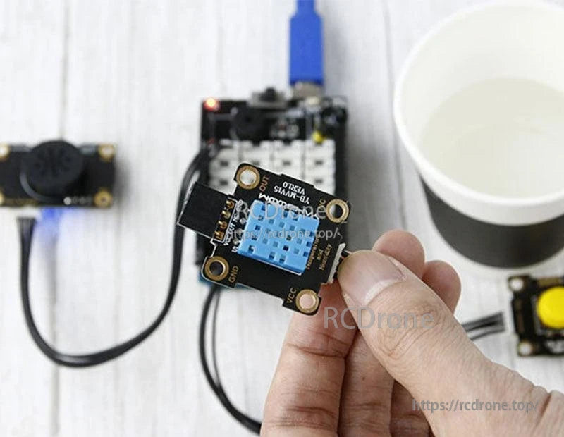 Handheld Yahboom DHT11 temperature humidity sensor module connected to a controller board in a test setup