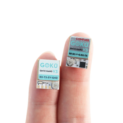 Flywoo GOKU GM10 Nano V3 GPS modules with labeled solder pads, shown on fingertips for size reference