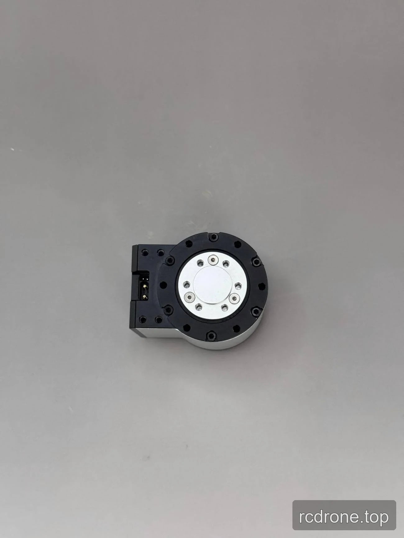 Black-and-silver motor housing with circular mounting face and connector