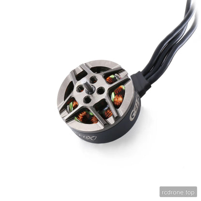 Top angled view of the GEPRC GR1404 motor with central shaft, mounting holes, exposed copper windings, and wires.