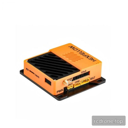 Rear-side angled view of the orange HexFellow computer with black vent grille and labeled RST, TRIG, STOP, PWR, OUT, CHG and BAT areas.