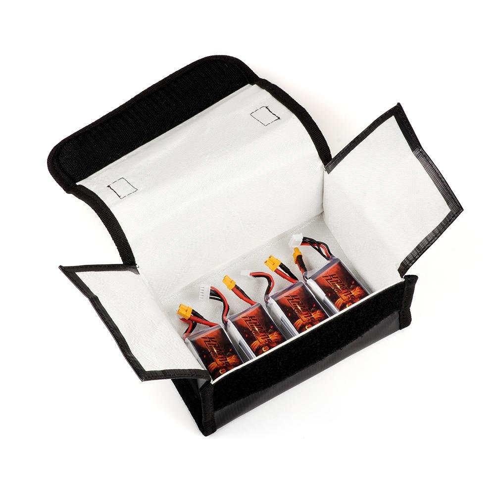 Open fireproof battery safe bag showing white interior lining and four RC LiPo batteries inside