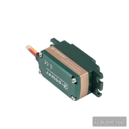 Underside of the green servo showing four silver cover screws, printed markings, copper-colored band, and mounting tabs.
