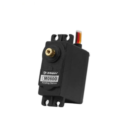 Black M0600 analog servo standing upright with exposed brass-colored splined shaft, front label, and mounting tabs.