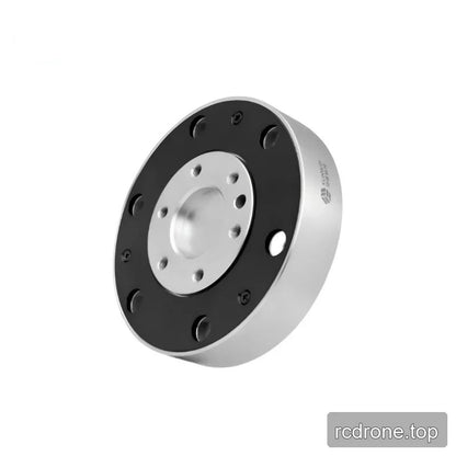Tilted circular sensor showing its black mounting face, recessed silver center, and right sidewall with a small logo marking.