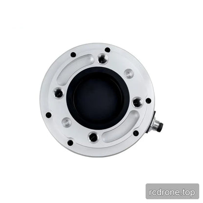 Top face of the circular sensor showing threaded holes, curved machined recesses, and a black central opening.